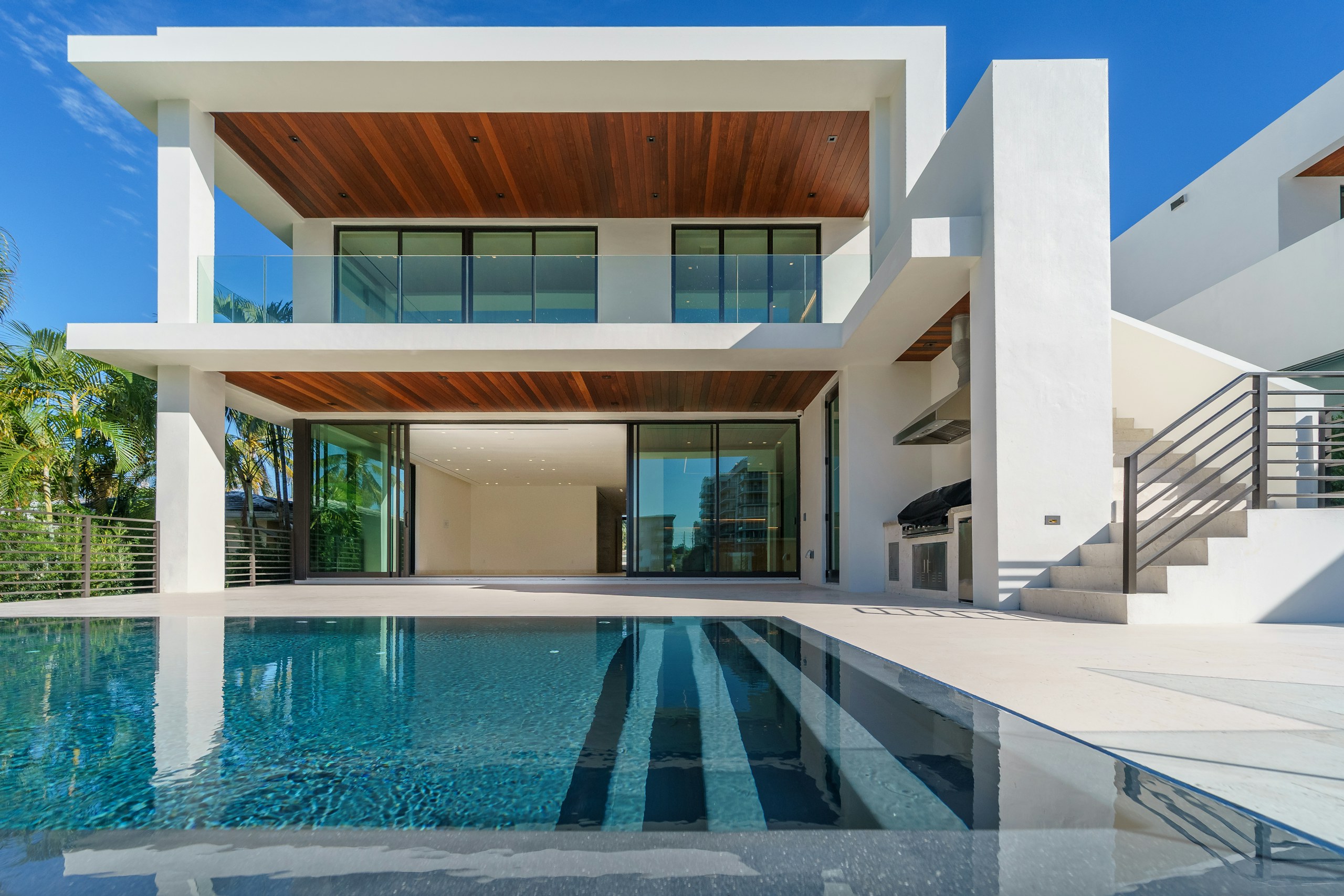 Modern double-storey home with timber ceilings and glass walls above an infinity pool